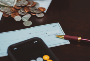 Checkbook on table with cash, calculator and pen