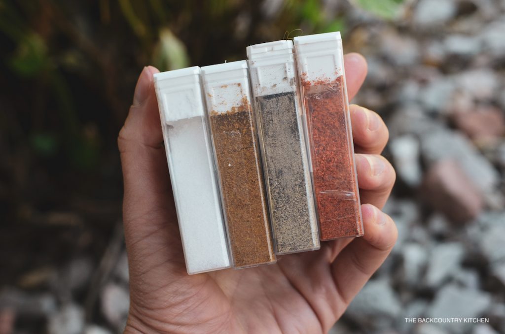 A hand holding four repurposed Tic Tac containers filled with spices
