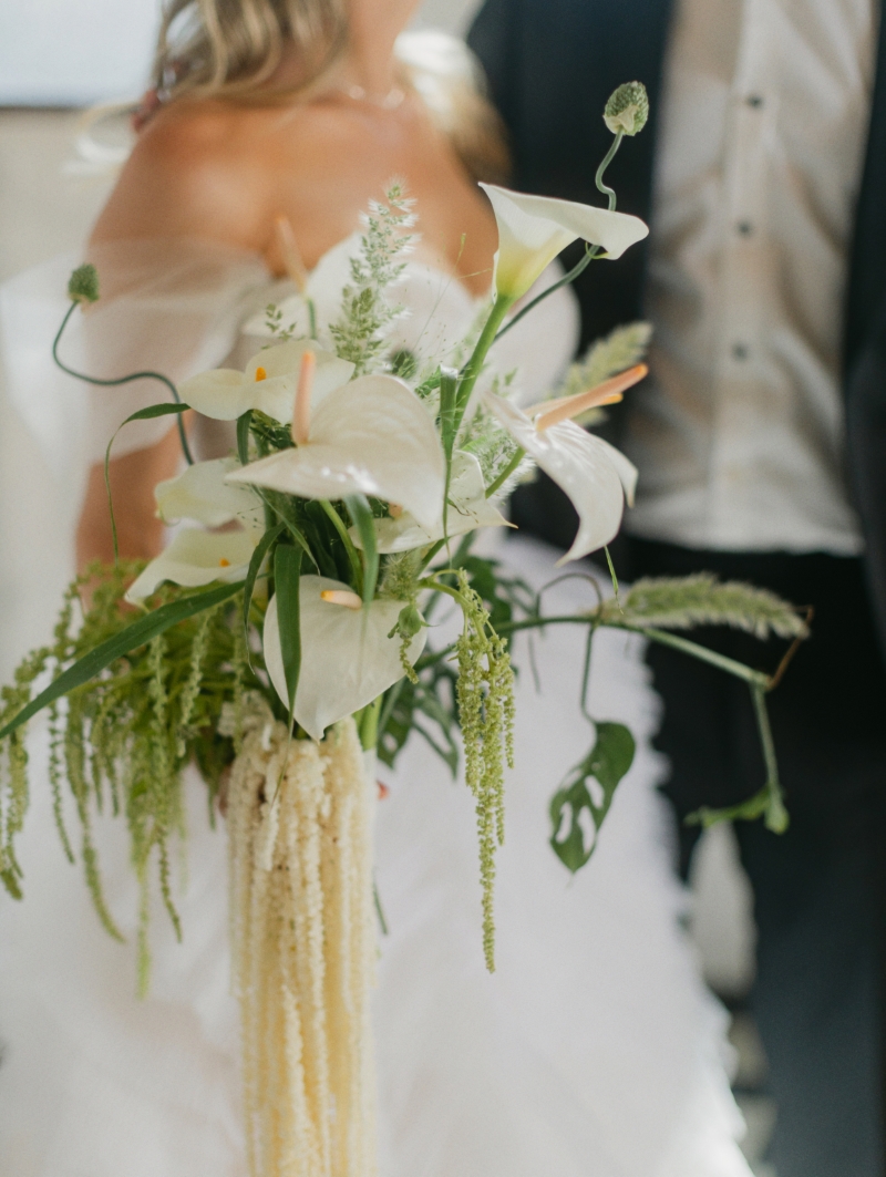 a bride holding her bouquet of calla lillies with descending greenery in downtown Los Angeles after her wedding ceremony, standing with her groom