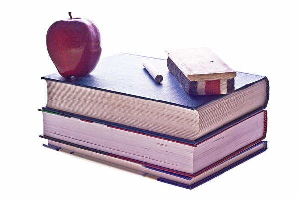 picture of two books ontop of each other with chalk, blackboard eraser and apple ontop.