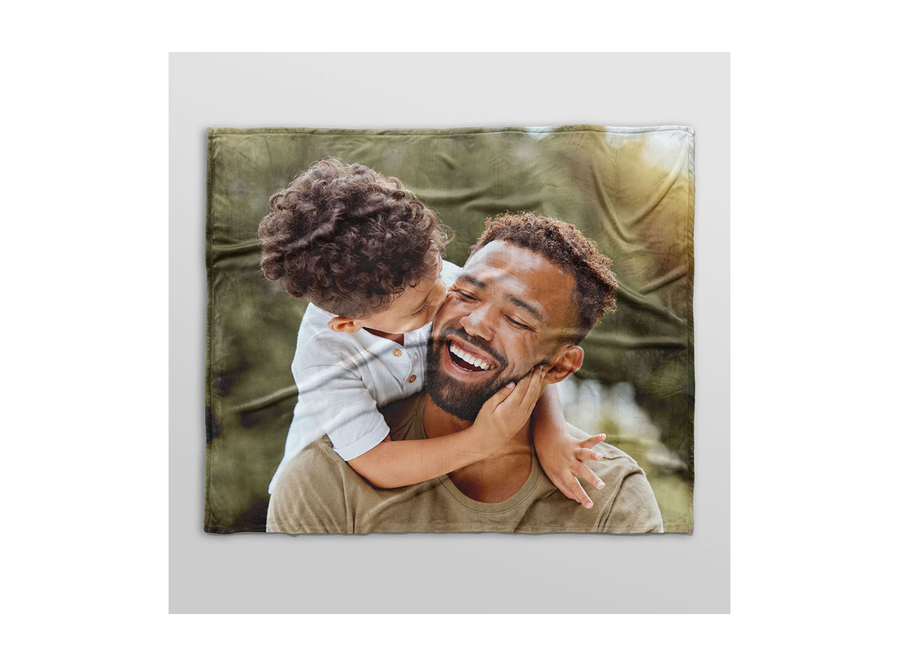 A fleece photo blanket showing an image of a young son and his father smiling together. 