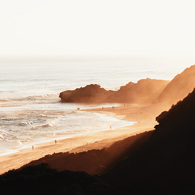 Photo of people walking on a beach at sunset