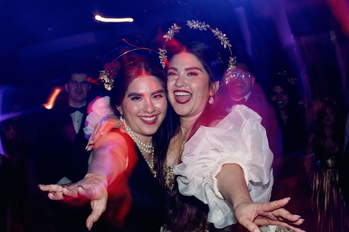 a bride posing with one of her bridesmaids at indoor wedding reception ballroom DTLA