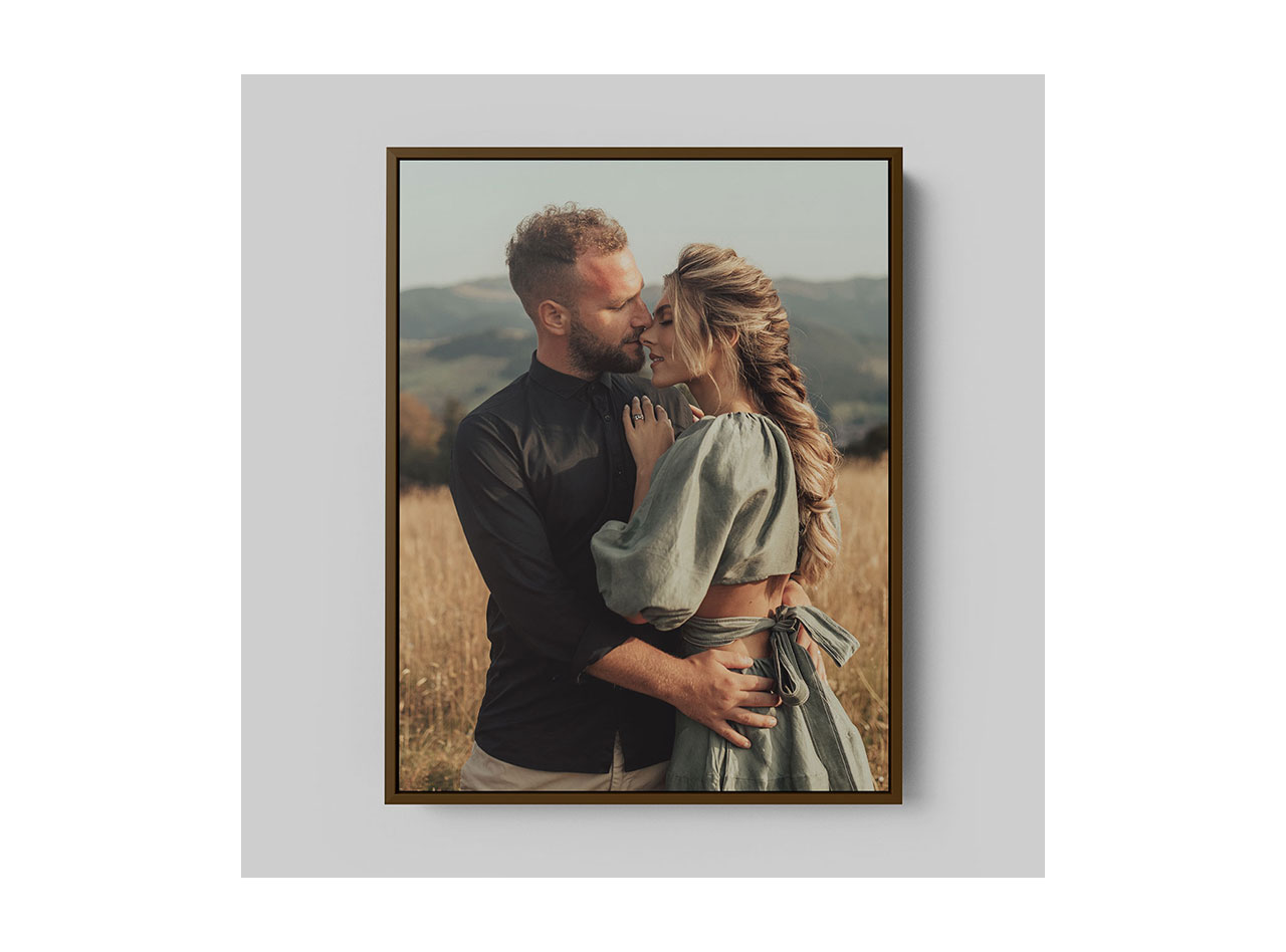 A framed canvas print portraying a man and woman embracing in a field