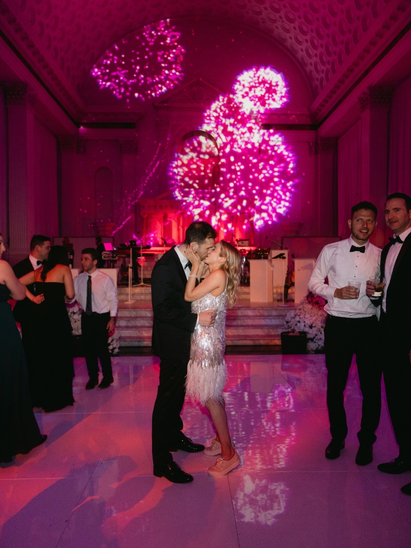 a bride and groom kiss in front of firework lights in a cathedral for their wedding reception in downtown Los Angeles