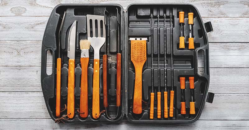 Essential grilling tools like a spatula, basting brush, skewers, knife, etc