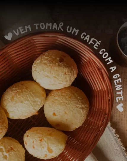 Foto de uma cesta de pães de queijo e uma xícara de café do lado