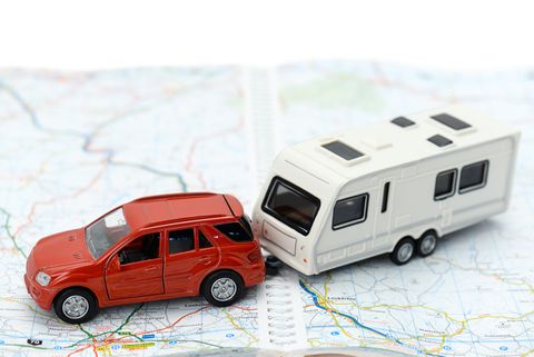 A red toy car towing a toy RV on a map