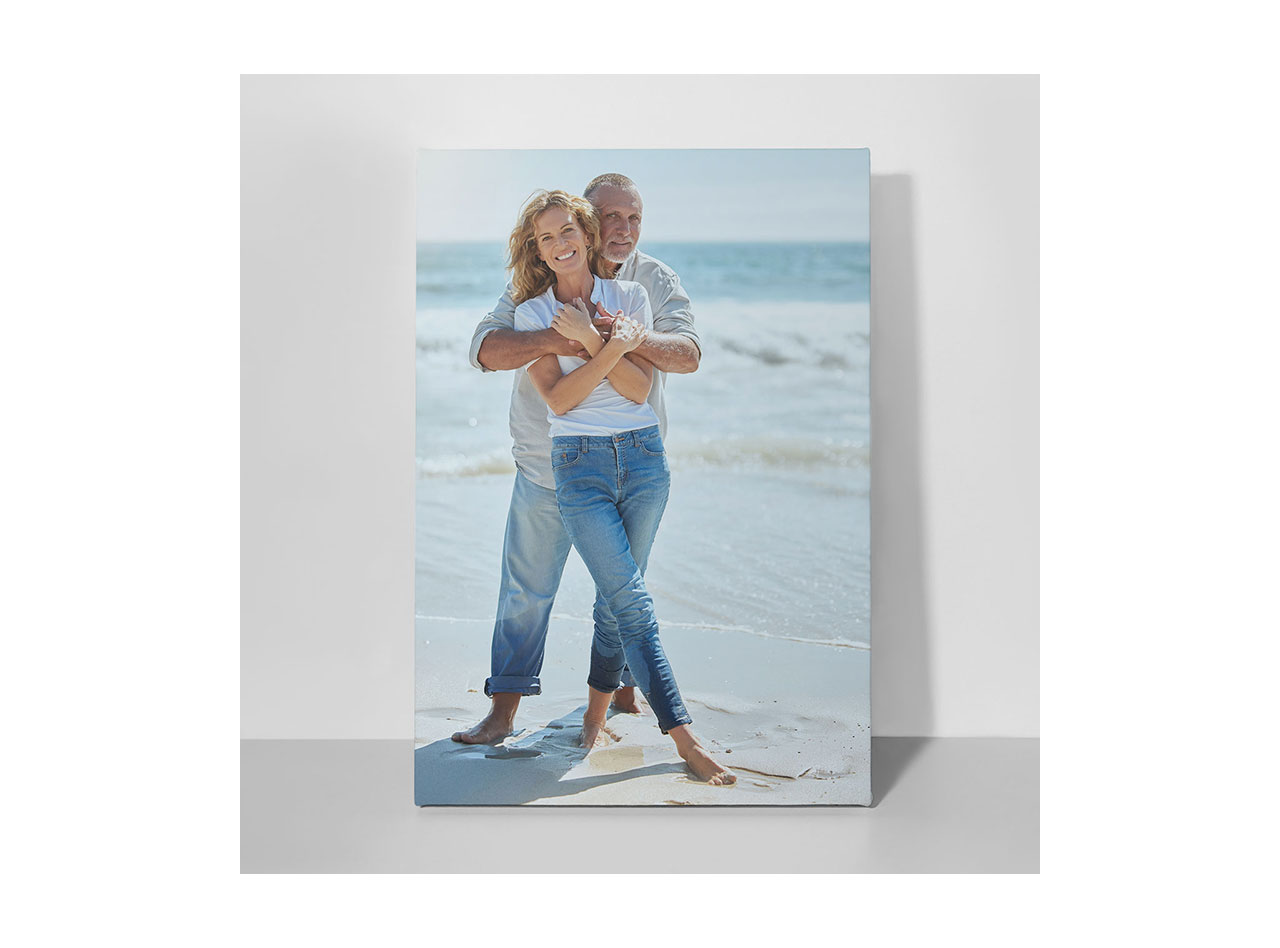 A canvas print featuring a photo of a couple smiling while embracing on a sunny beach
