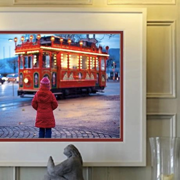 A framed photo of a child looking at a bus hung on a wall