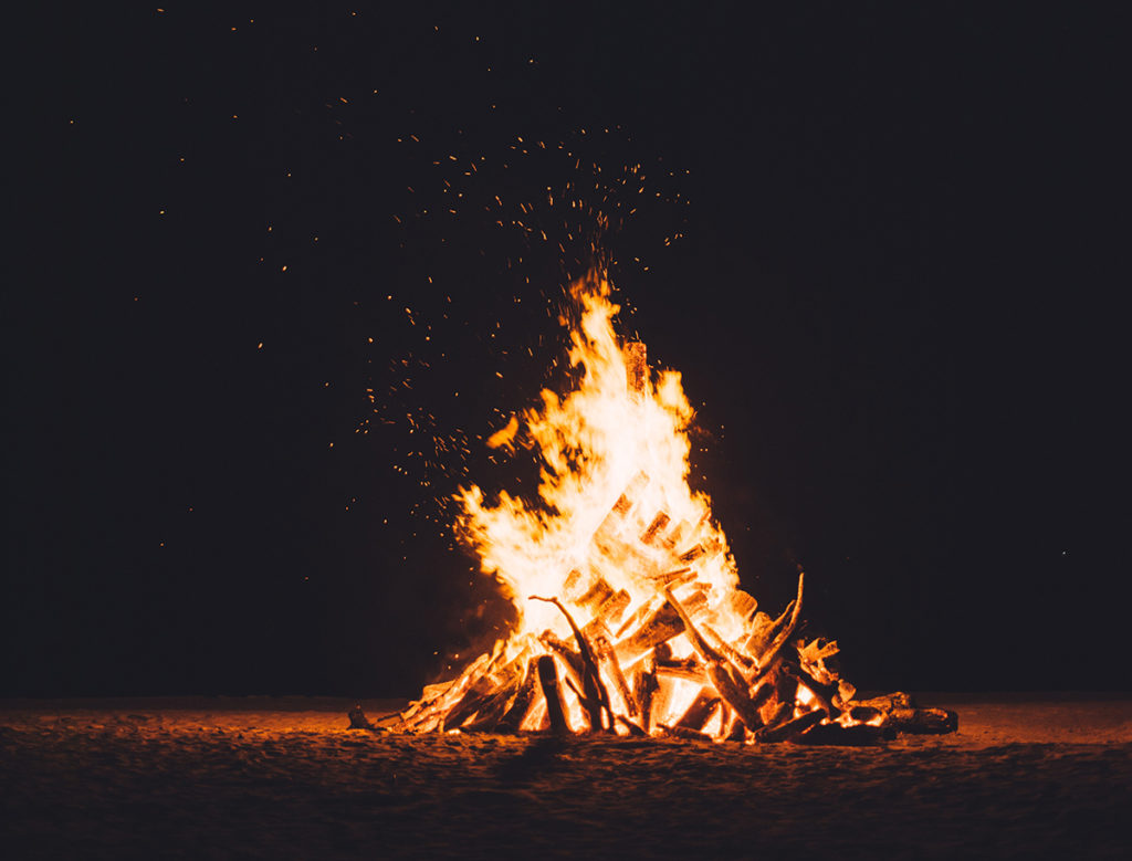 A beautiful bonfire sits beneath a starry sky on a chilly fall night.