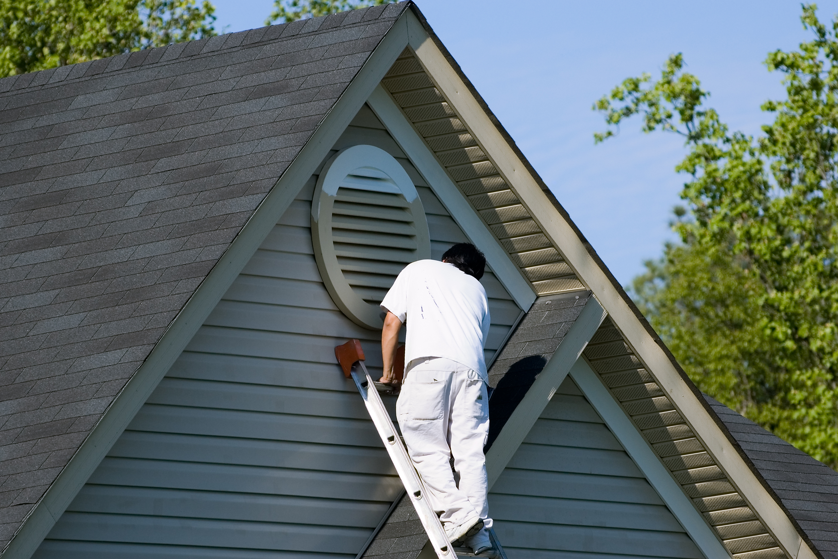 Painter painting at roofline of home