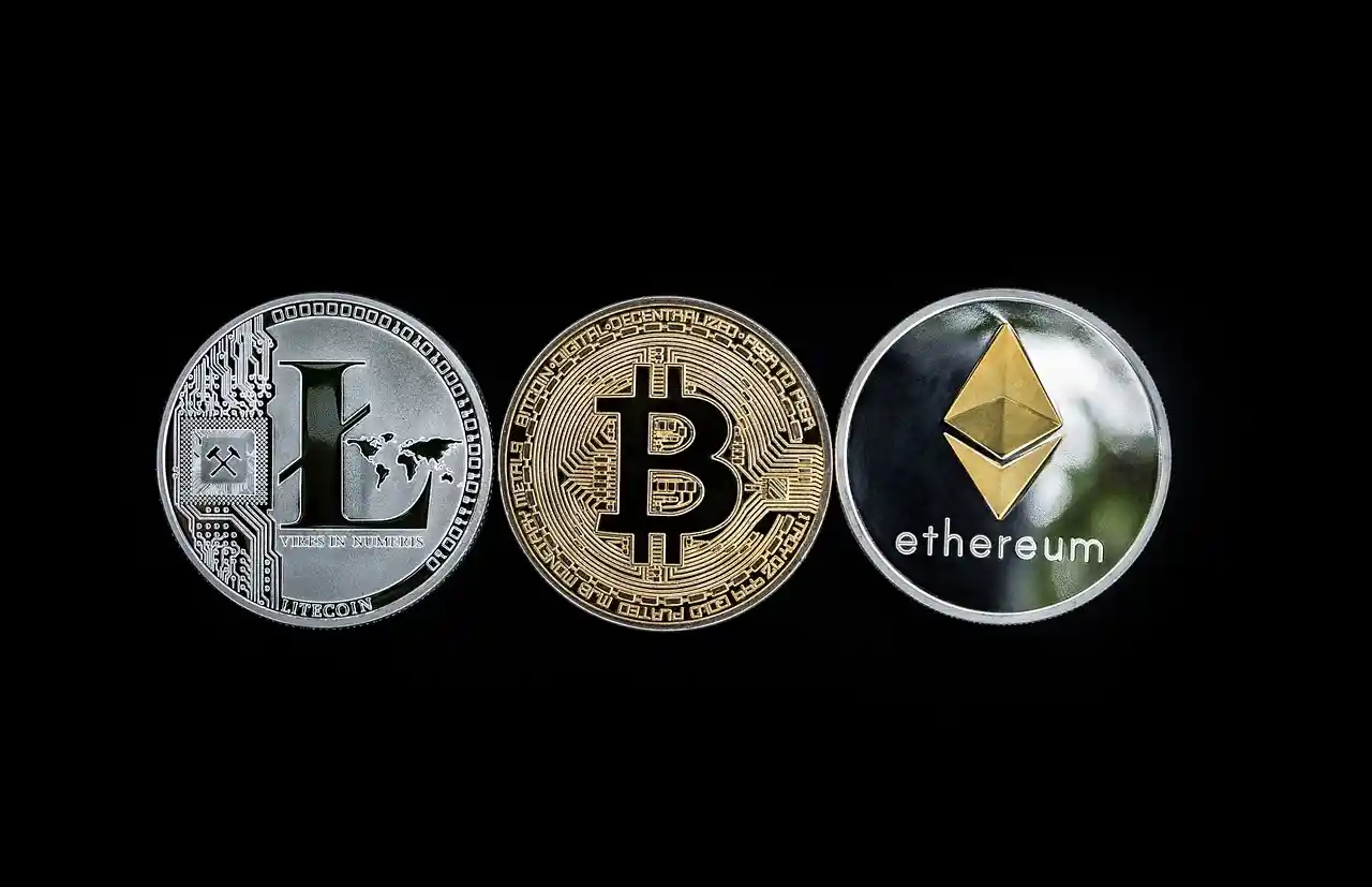 Representación física de las monedas de Bitcoin, Ethereum y Litecoin en un fondo negro.