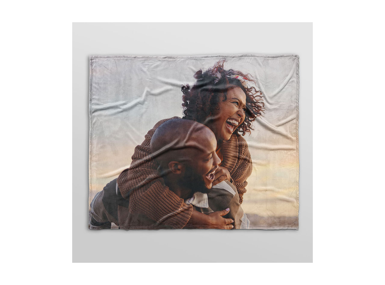 A photo blanket featuring a printed photo of a happy couple embracing on the beach. 