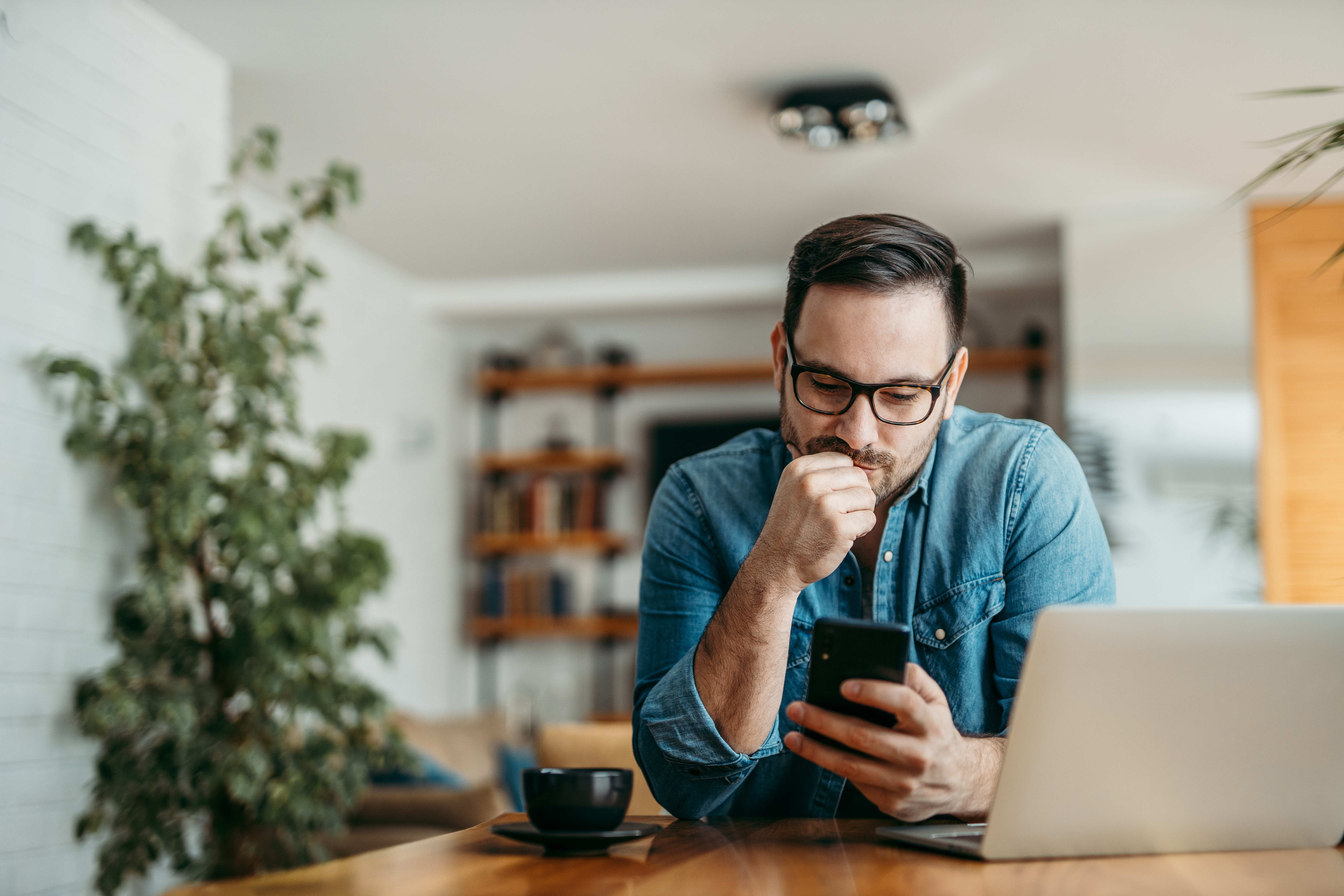 Man looking at phone filing taxes at home