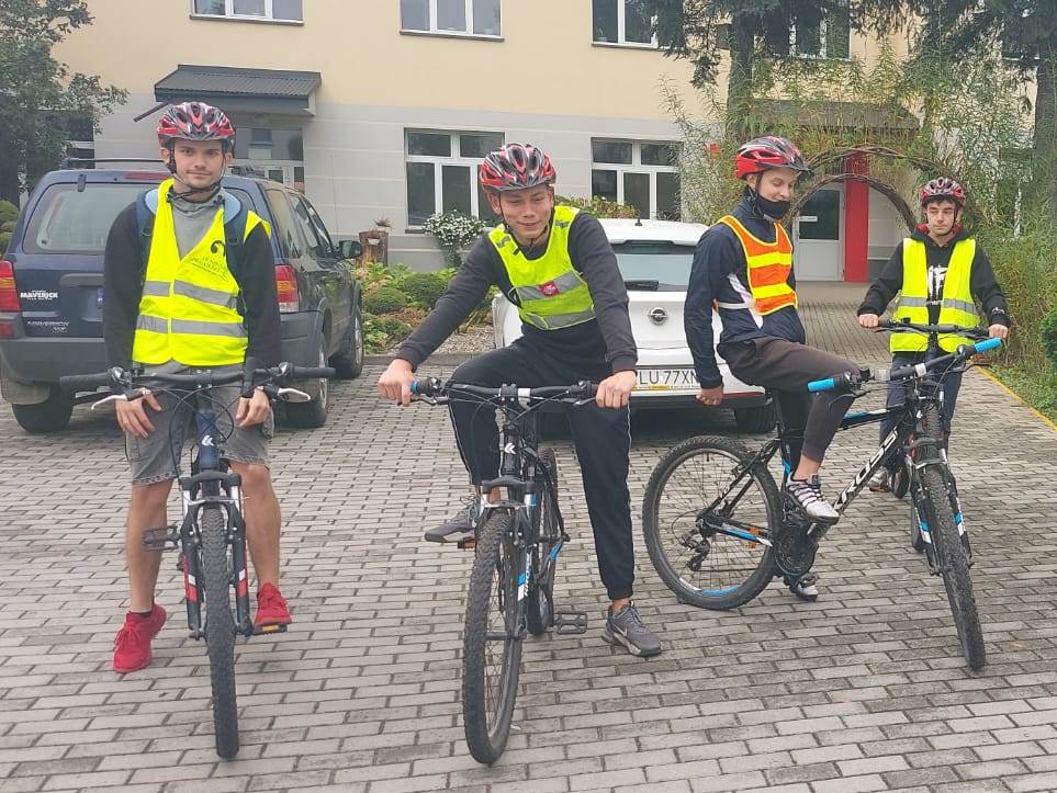 Rajd rowerowy | Wychowankowie MOW w kamizelkach odblaskowych i kaskach siedzą na rowerach przed budynkiem MOW..jpg