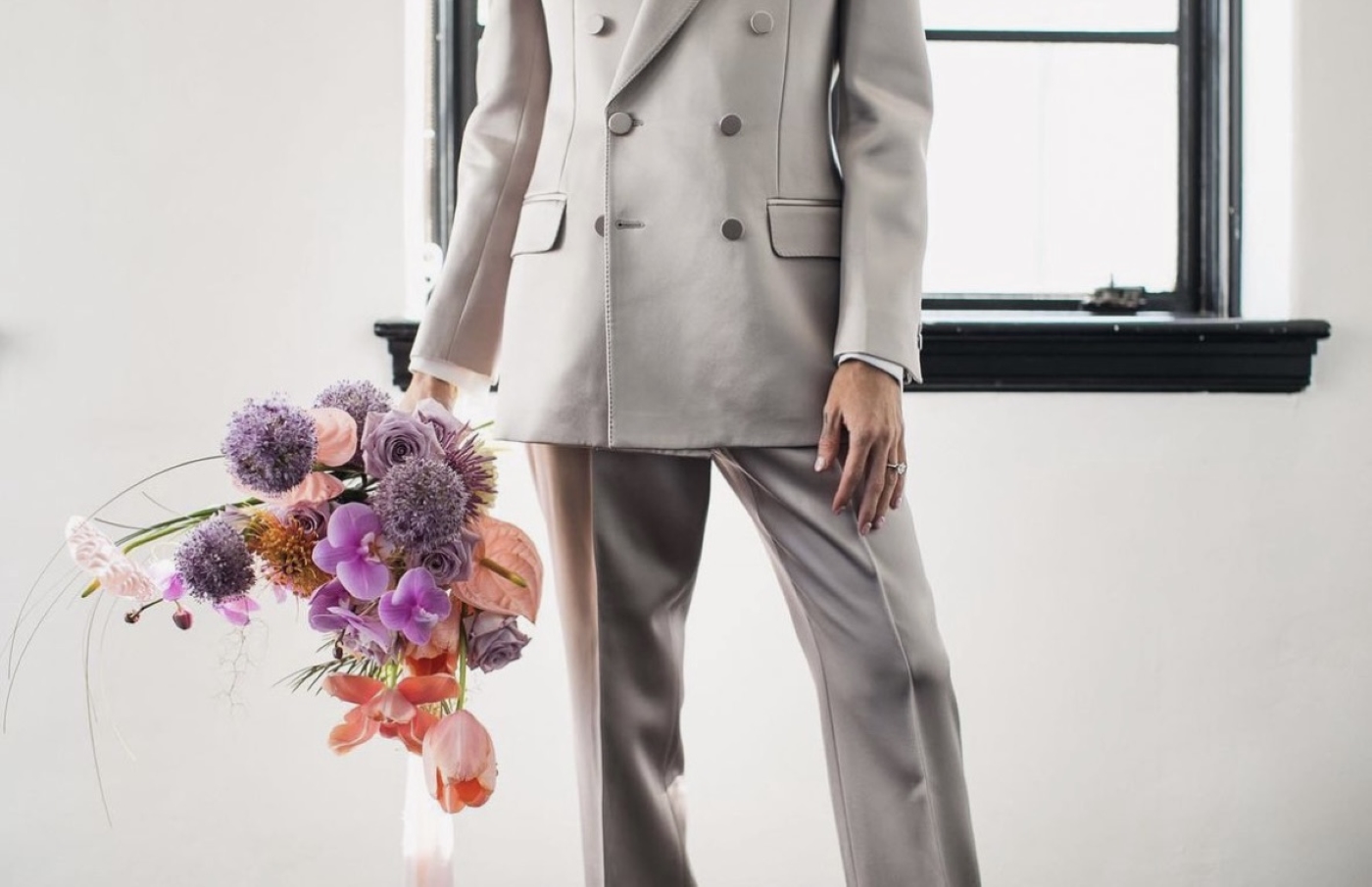 groom holding purple and pink flowers 