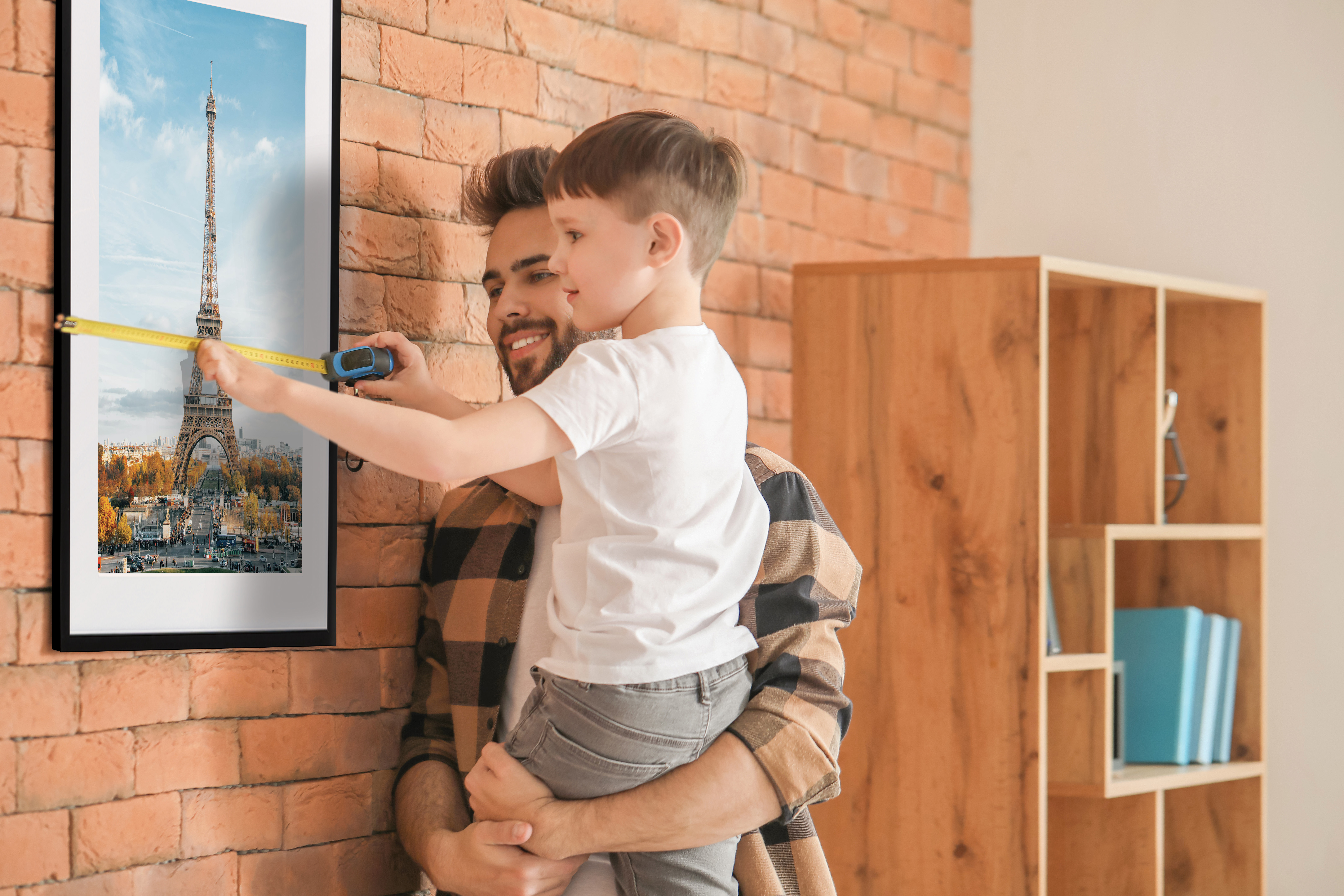 Father and son measuring a framed print