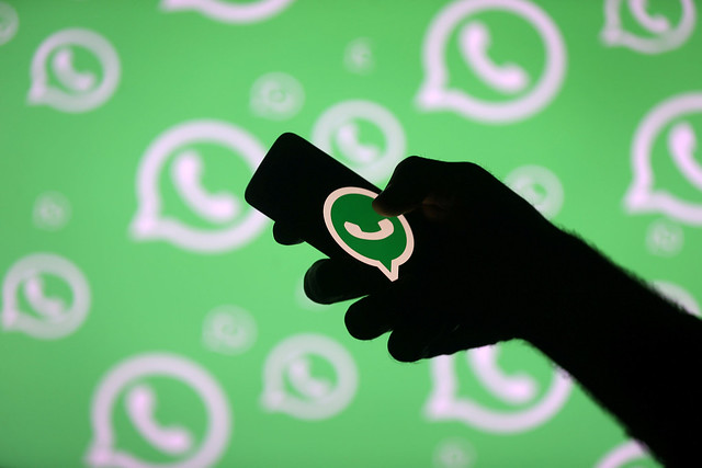 A phone held in hand, with a big WhatsApp icon displayed on the screen