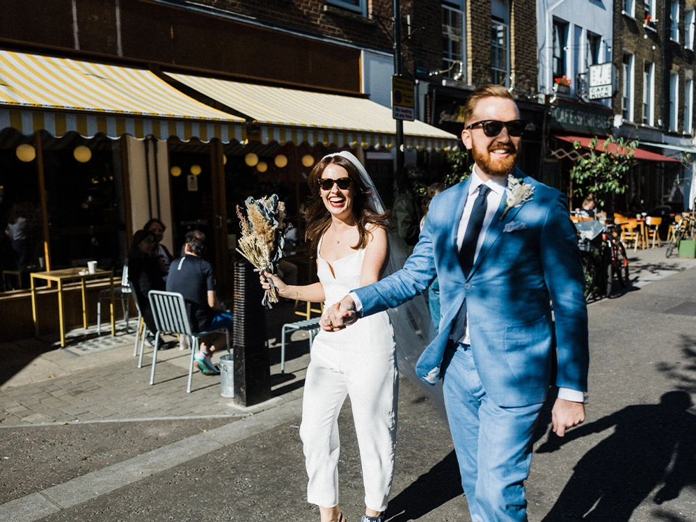 Modern couple on their wedding day, walking through Exmouth Market