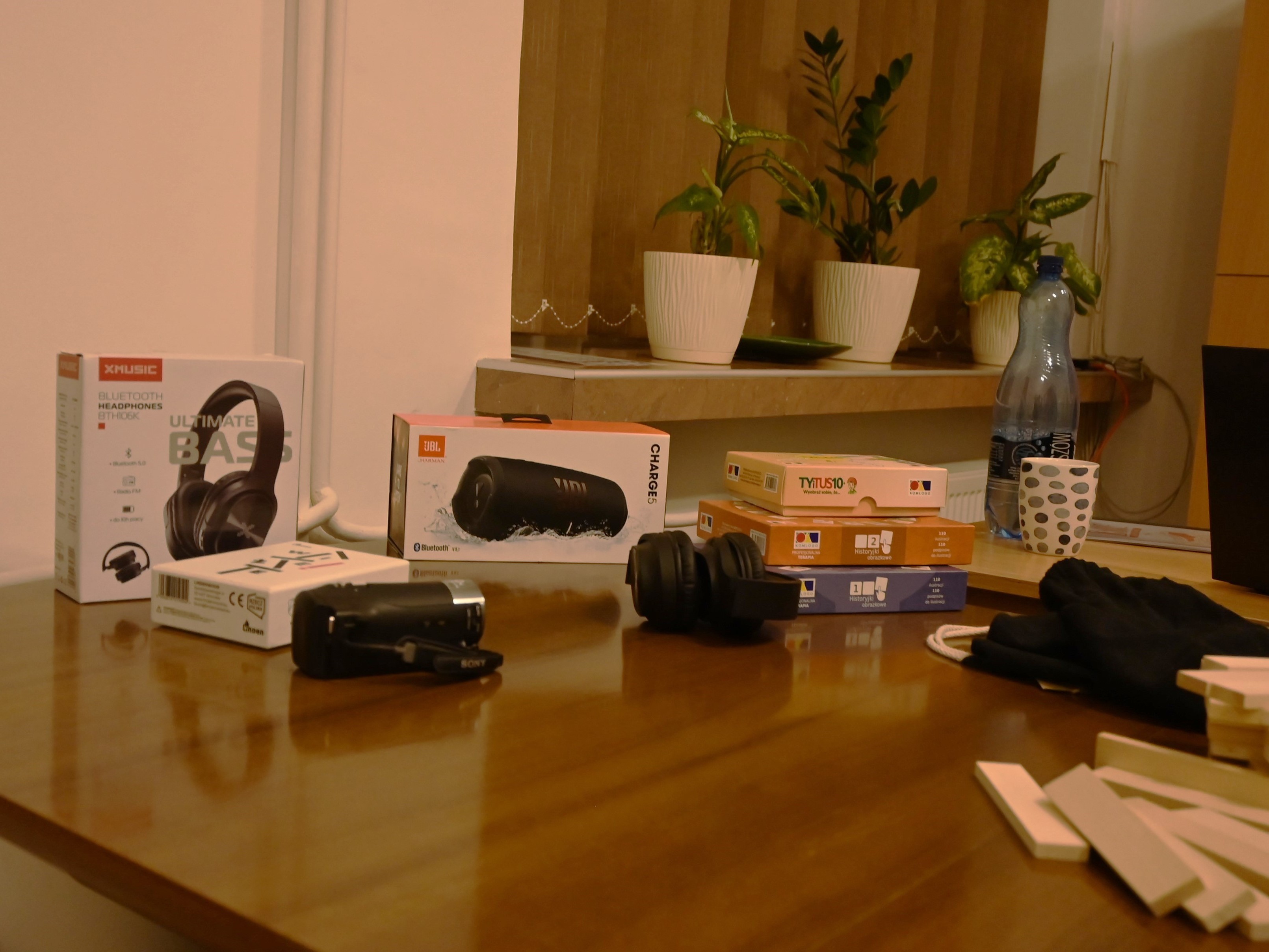 Zakończenie projektu Fajna Ferajna | Blat stołu, na którym leżą rzeczy kupione na portzeby projektu - klocki, gry planszowe, a także słuchawki, głośnik, sprzęt elektroniczny.JPG