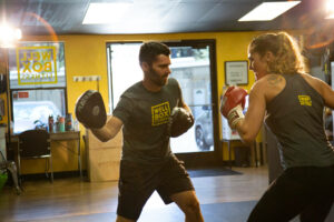 Athletic trainer doing boxing drills with client