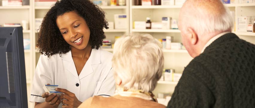 woman pharmacist helping elderly couple