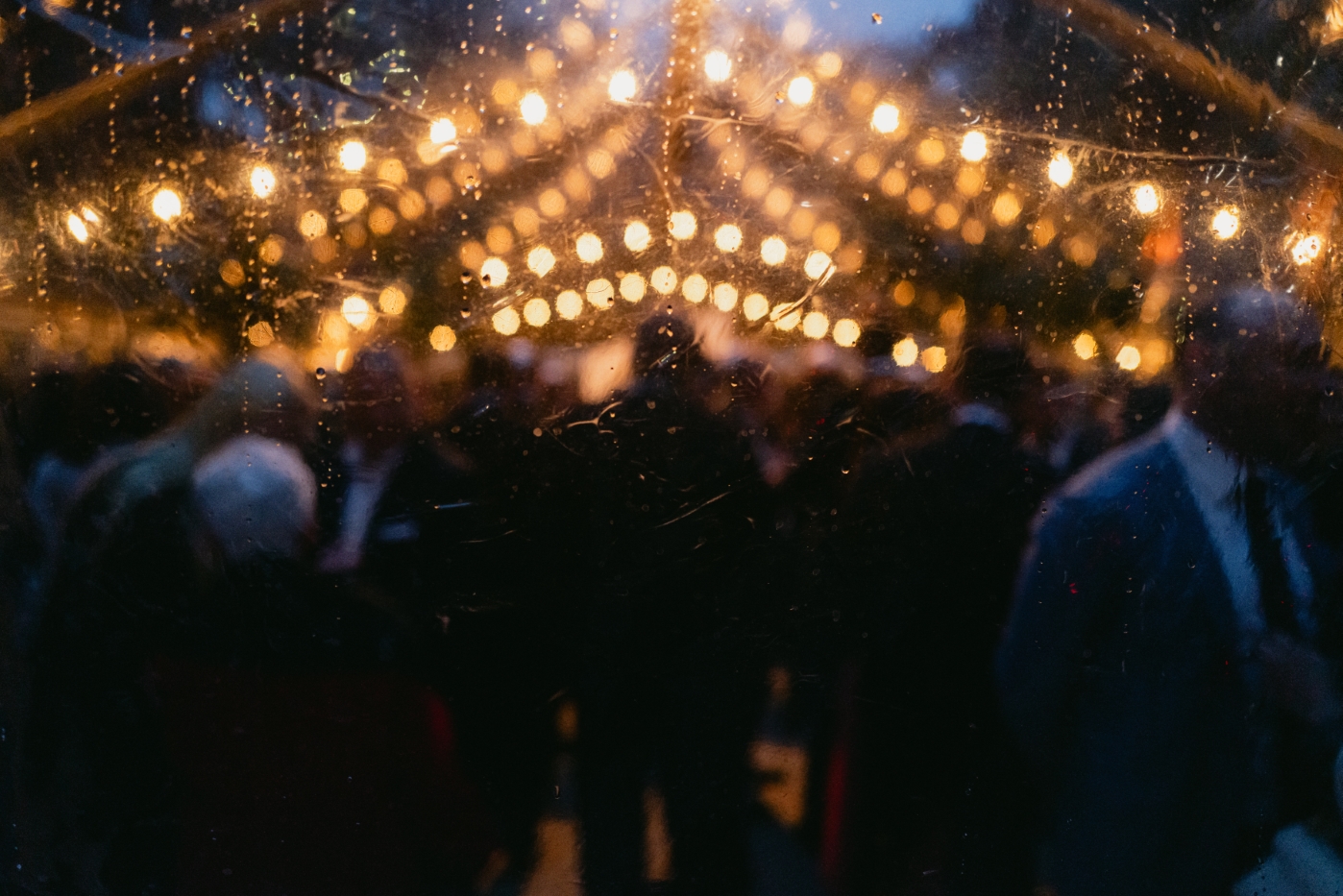 guests stand under a tent under rows of string lights outdoors at their downtown Los Angeles wedding reception