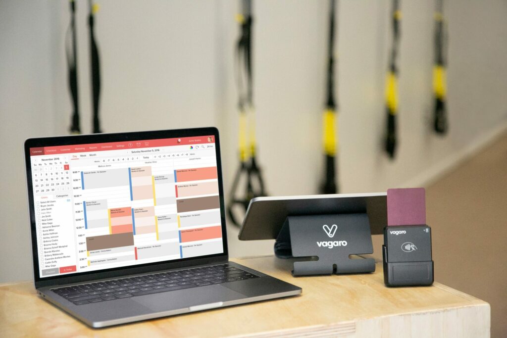 Vagaro gym management software on laptop, tablet and wireless card reader