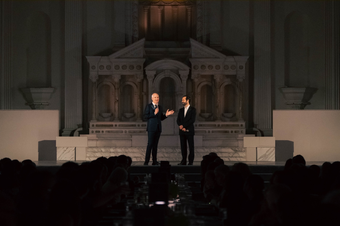 two men in suits stand on stage to address an audience at their gala at Vibiana in Downtown Los Angeles