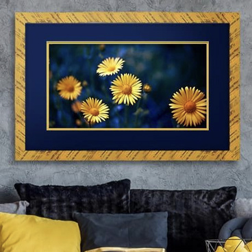 Photograph of golden flowers within a golden frame hung on a wall