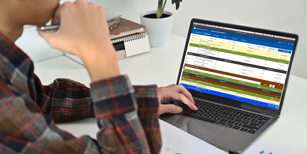 Man looking at New Movie Magic Scheduling stripboards on laptop screen