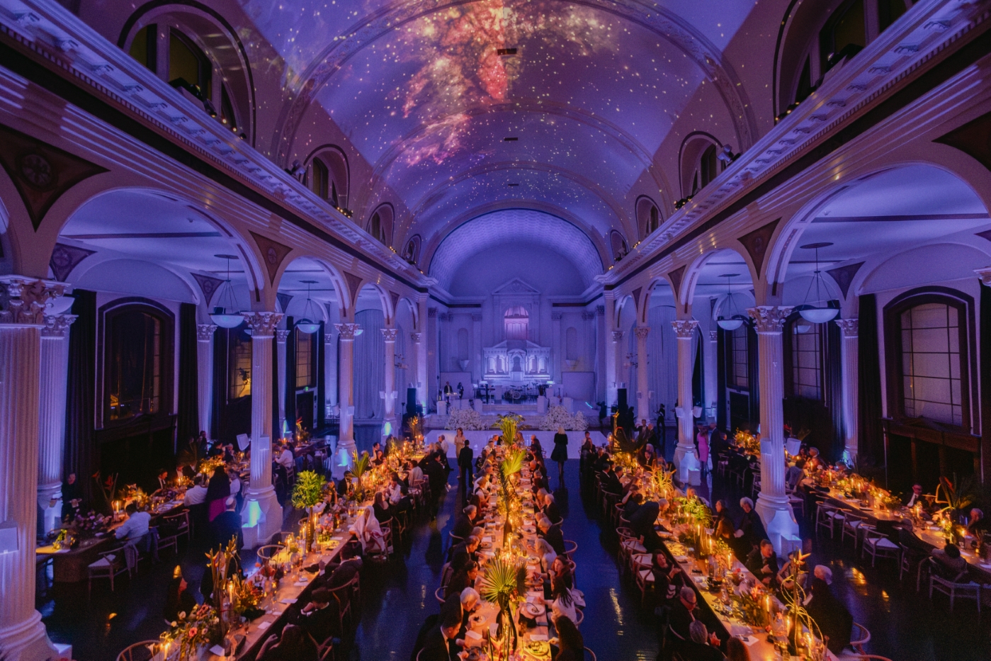 guests eat at a wedding reception in a cathedral downtown Los Angeles with colorful light projections