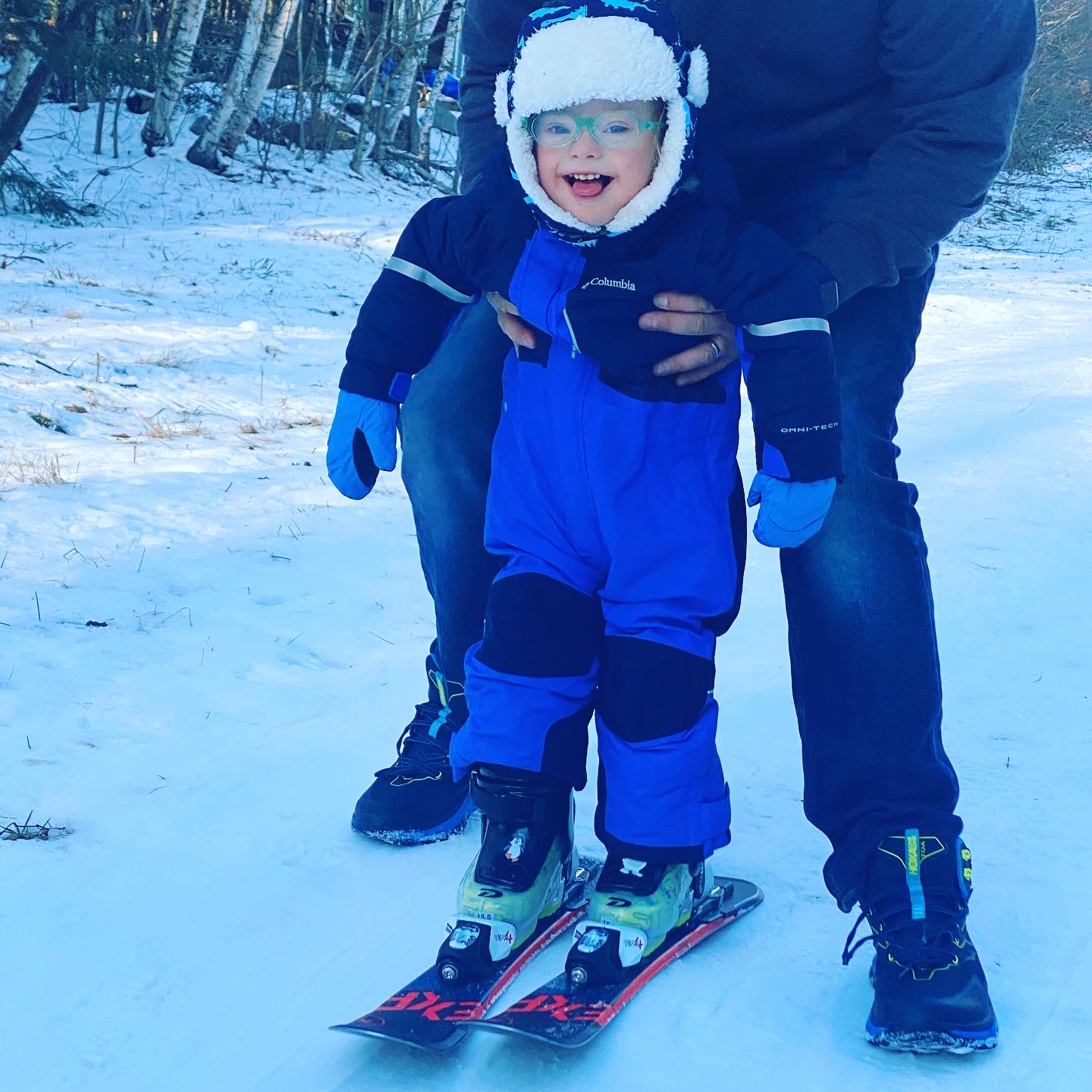 A young girl with down syndrome in a full snow suit and skis