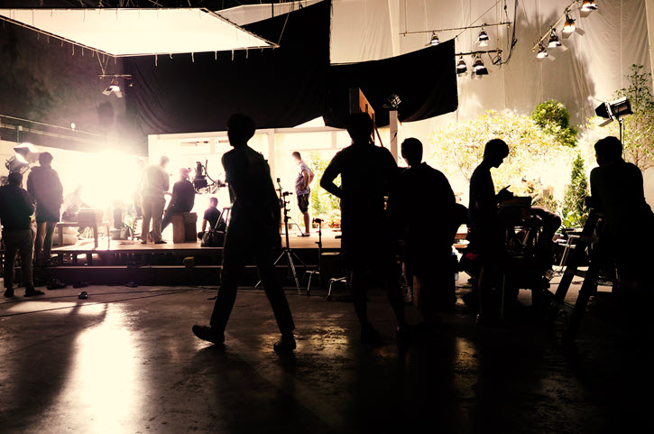 Moneypenny page hero image. Photo of behind the scenes on production set with crew in silhouette.