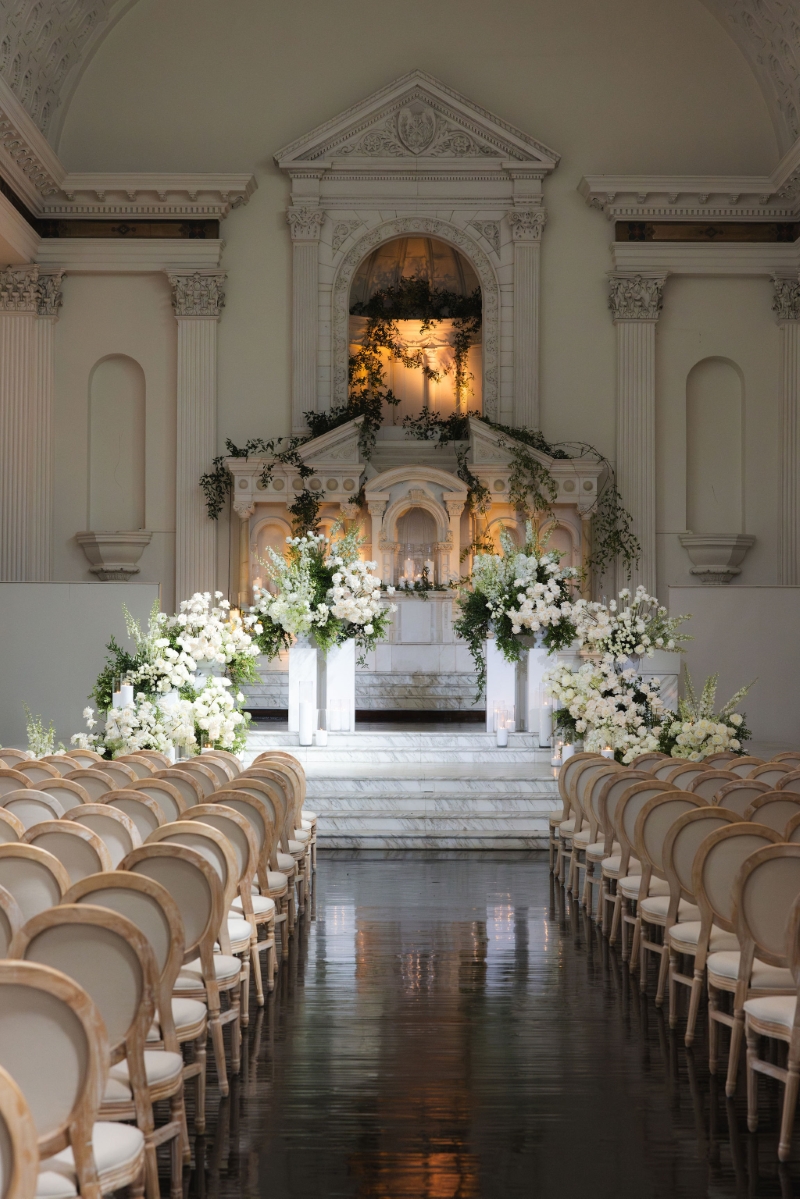 a cathedral altar set up for a wedding ceremony with white roses and white chairs