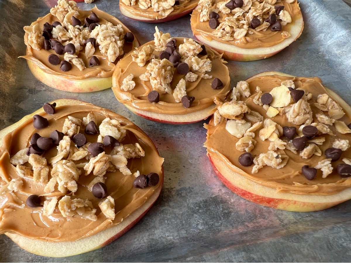 Apple "pizzas," one of the best camping snacks for kids, with peanut butter, nuts, and chocolate chips