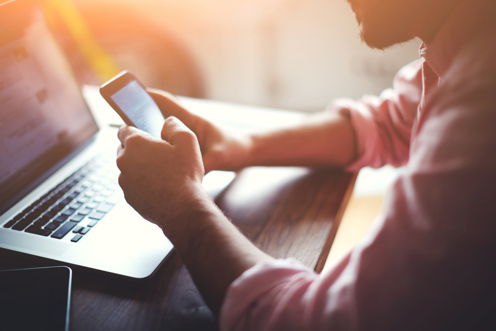 Stock image of man at laptop using a phone