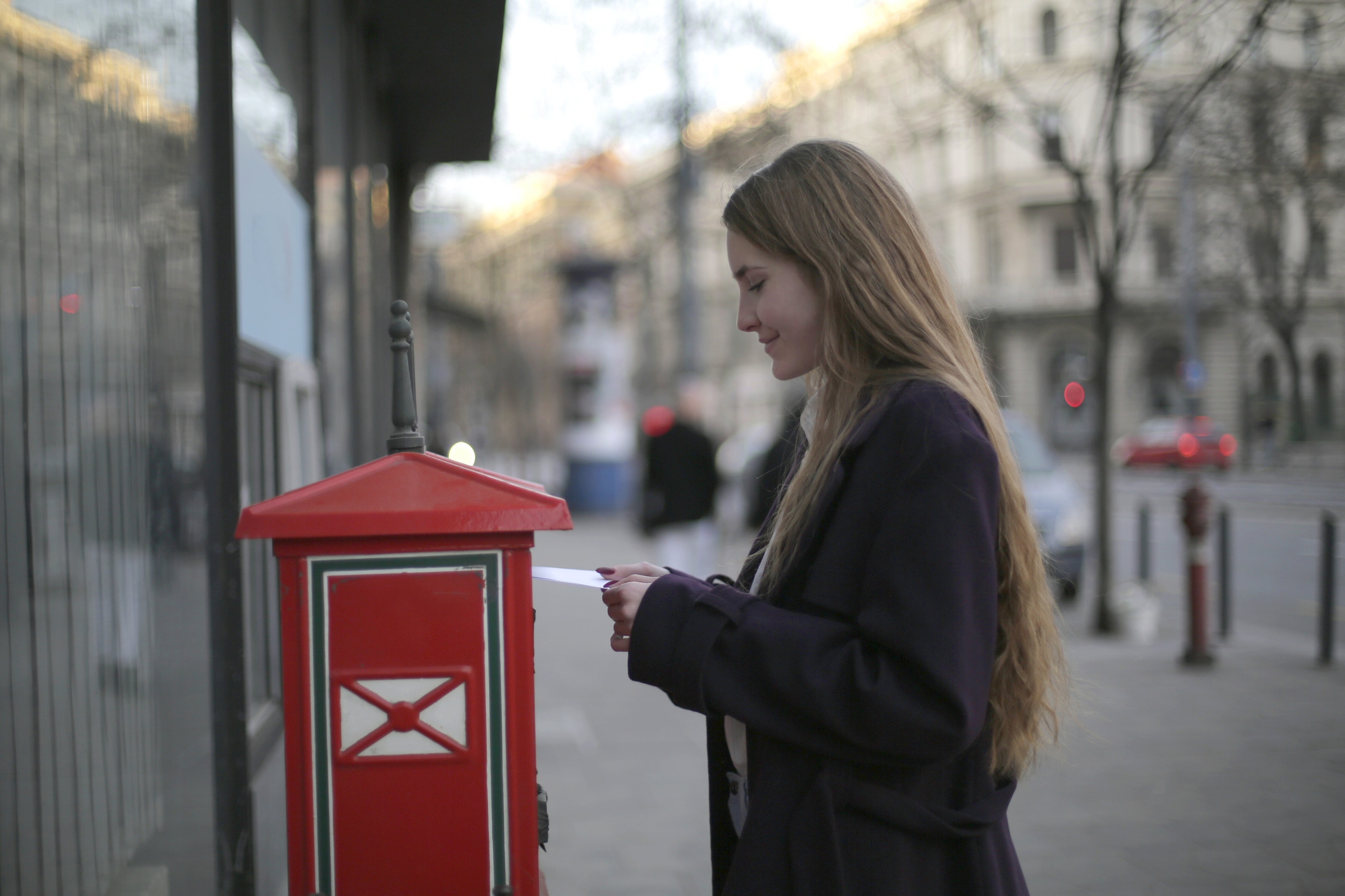 Kobieta wrzucająca list do skrzynki pocztowej
