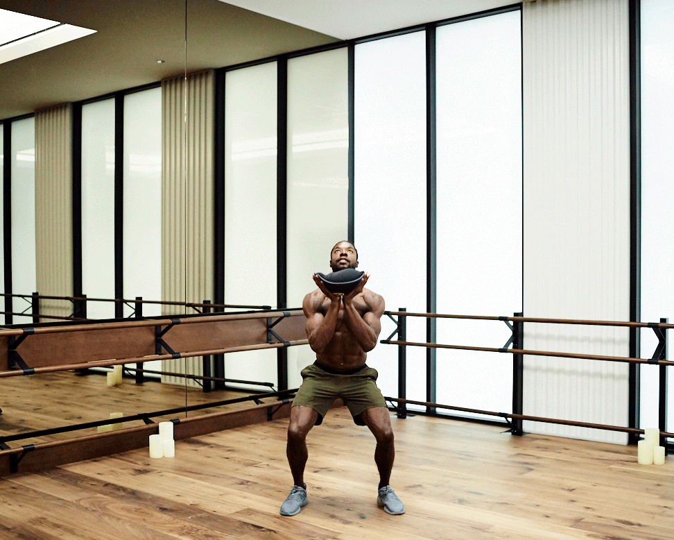 Moving image of Devin Buchanan doing a squat toss in a gym studio