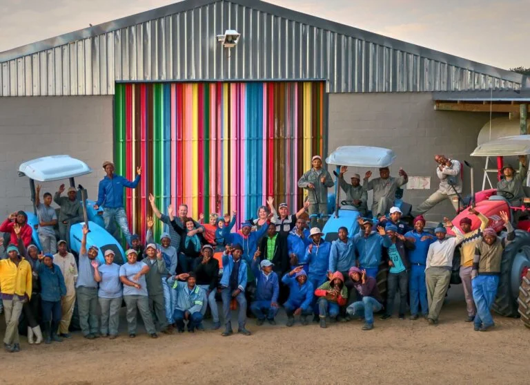 A group of people in front of a supplier warehouse waving.