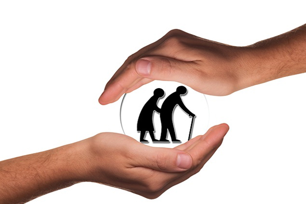 two hands gently placed on a globe with an elderly silhouette walking.