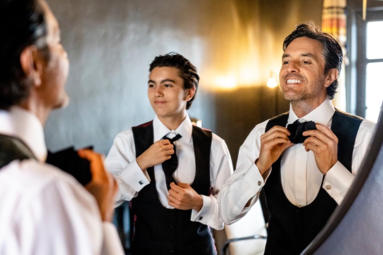 groom and groomsmen looking in mirror to get ready