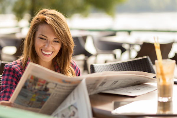 attractive redhead woman reading a newspaper for small business marketing