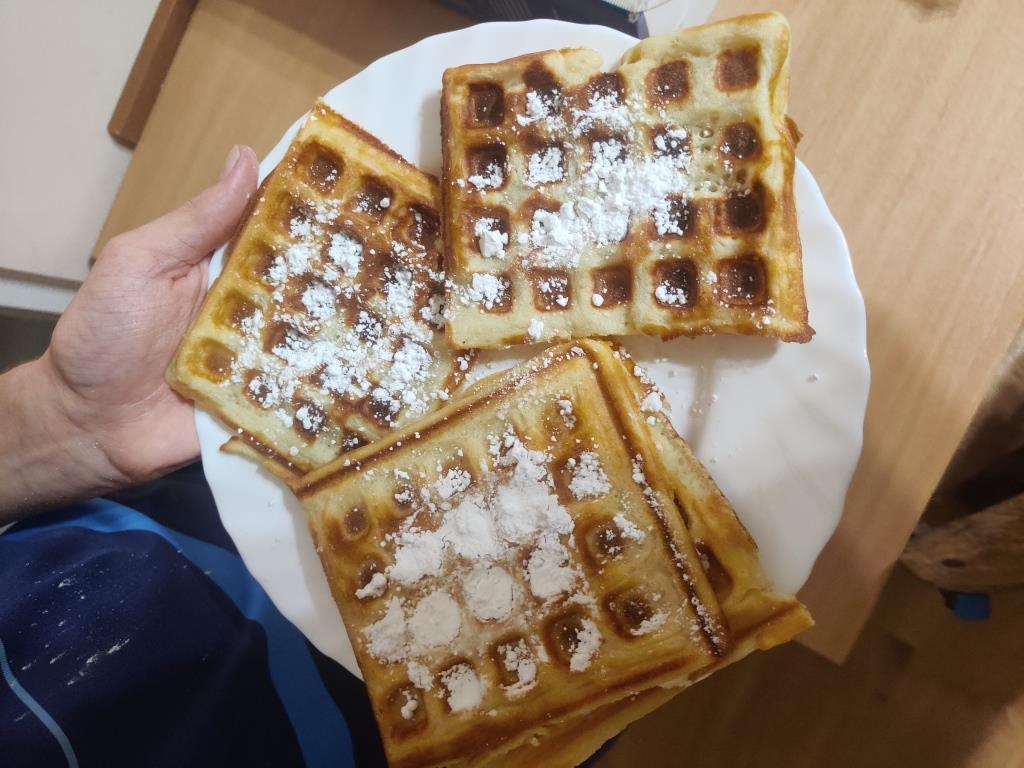 Zajęcia czasie wolnym | Zbliżenie białego talerza z goframi posypanymi cuktem pudrem..jpg