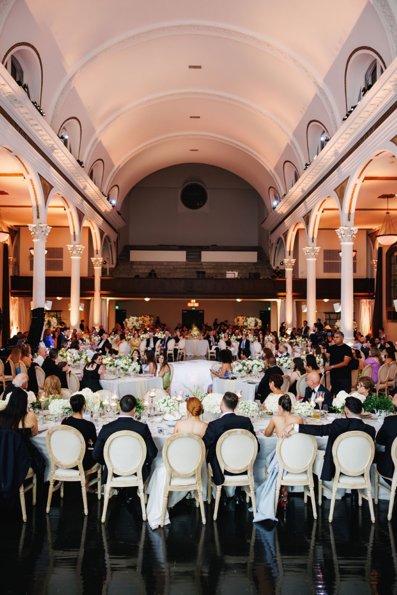 a wedding reception in a cathedral with wedding guests listening to speeches