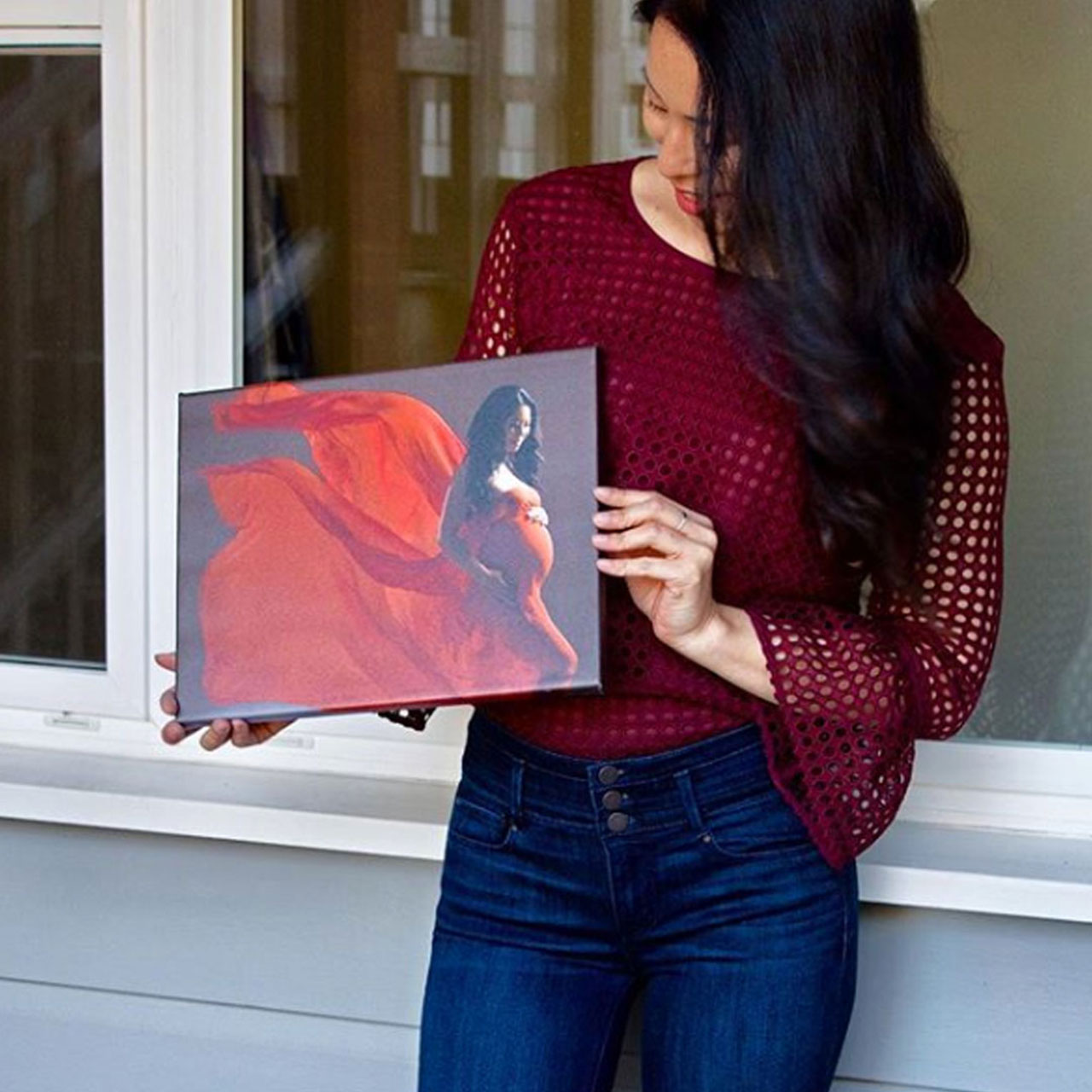 Woman holds a custom canvas that depicts a photo of herself posing in a red dress