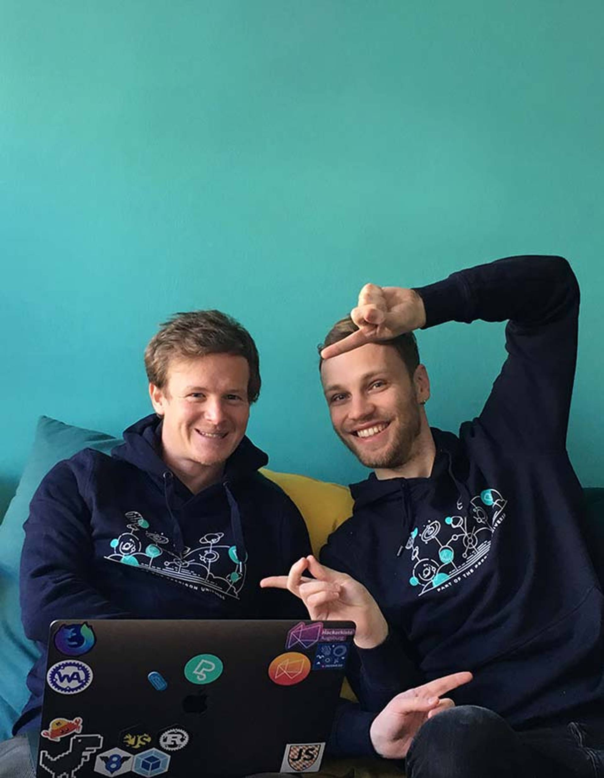 Zwei Mitarbeiter der Peerigon Agentur für Softwareentwicklung zeigen ihre neuen Pullover