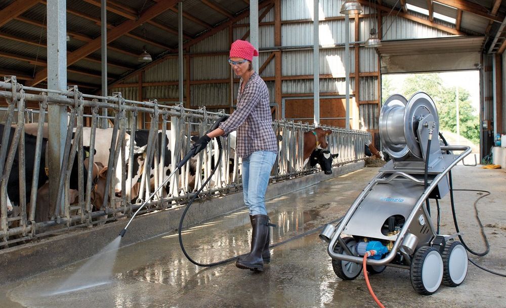 Woman cleaning stable with cleaning machine