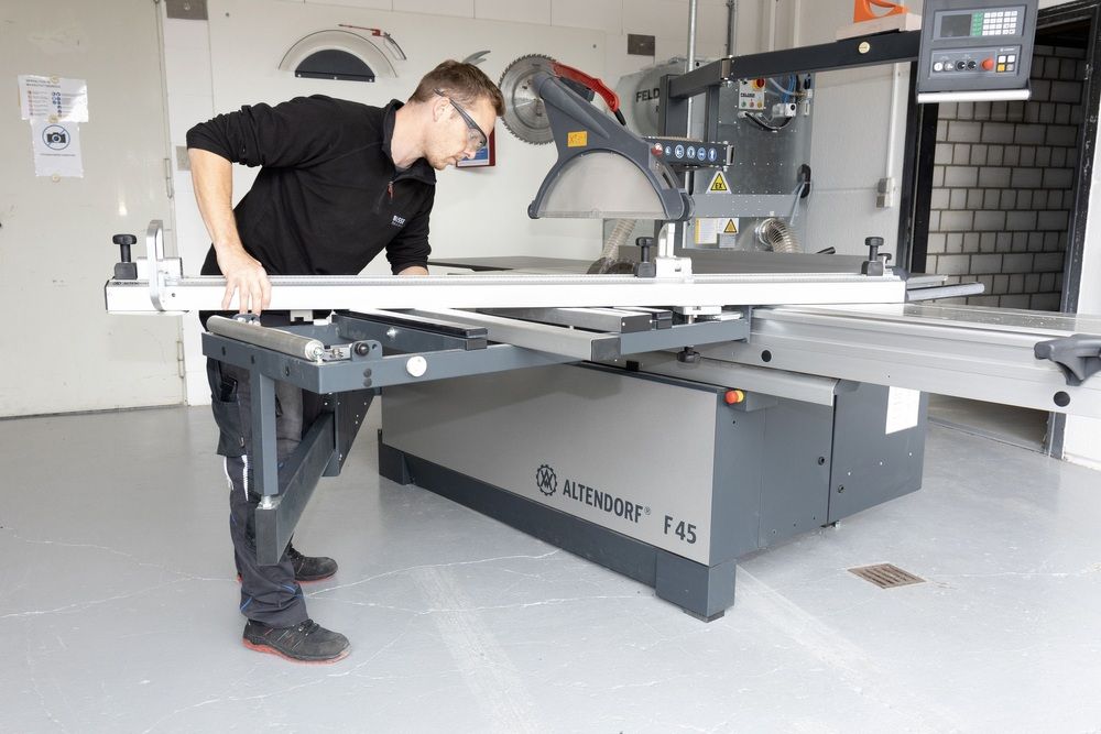 A man can be seen from the side operating a circular saw.